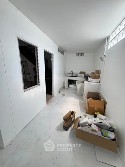 Spacious white-walled room under renovation with boxes and construction materials.