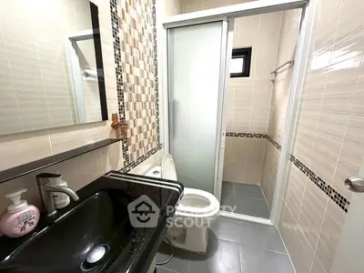 Modern bathroom with sleek black sink and glass shower enclosure