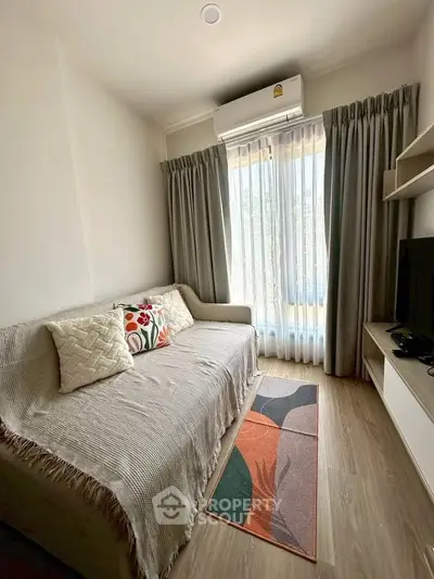 Cozy living room with modern decor, featuring a comfortable sofa, stylish rug, and natural light from large windows.