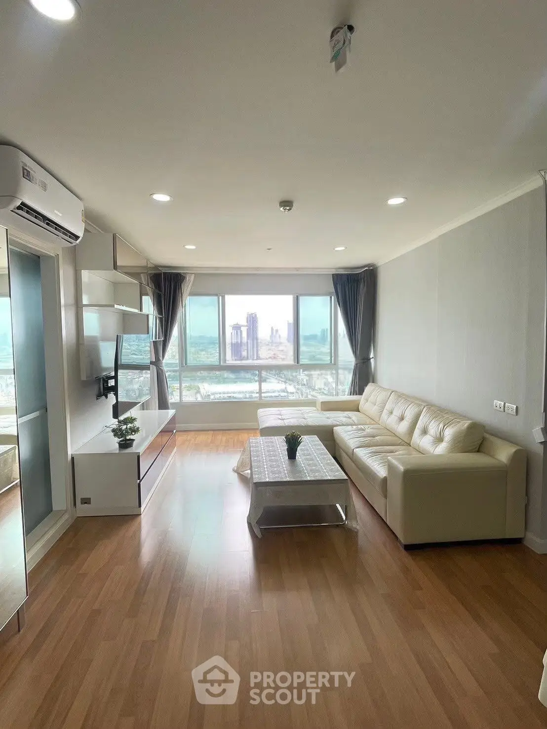 Spacious living room with city view, modern decor, and natural light