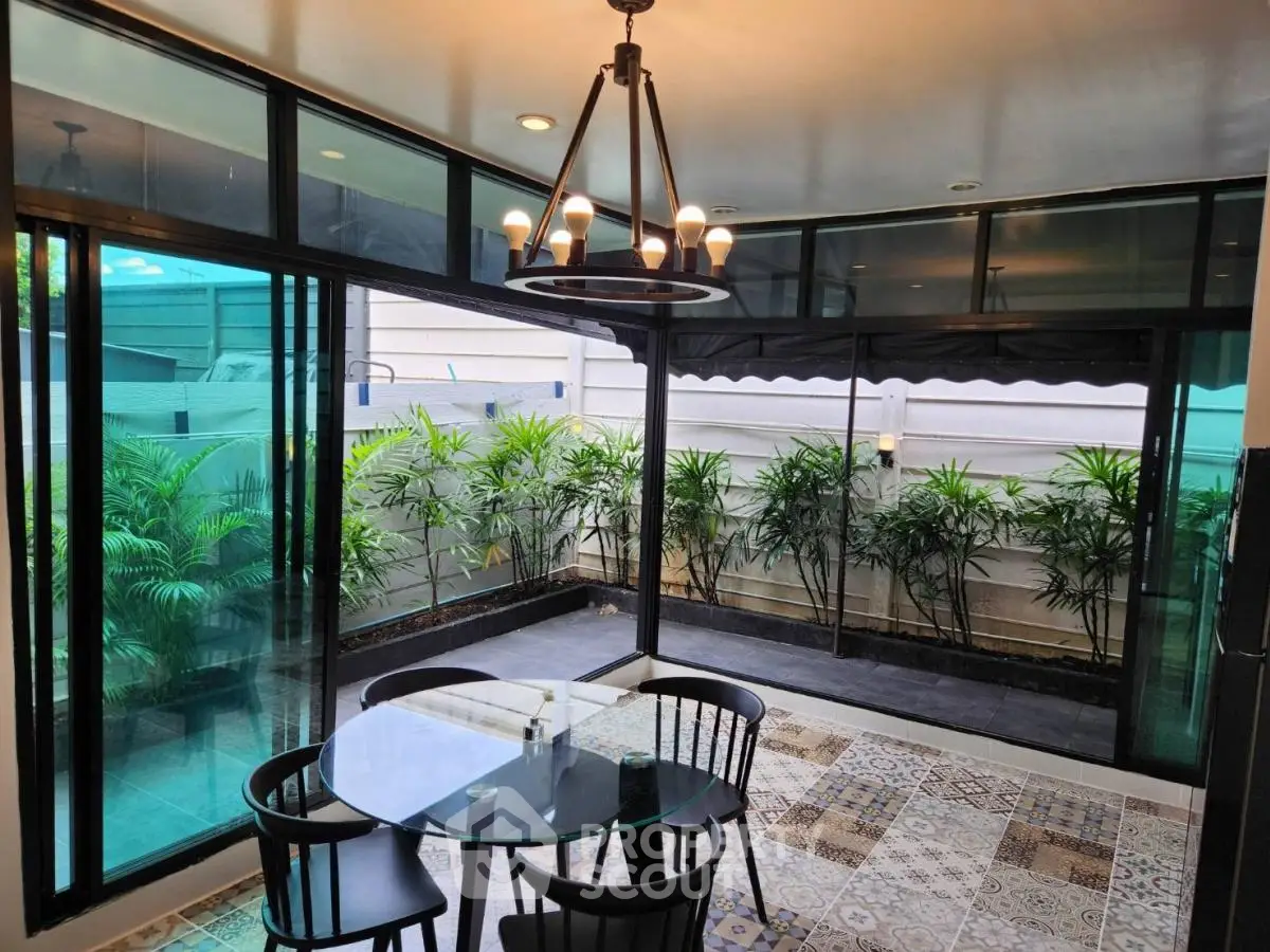 Charming dining area with glass walls overlooking lush garden, perfect for serene meals.