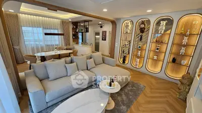 Luxurious living room with elegant decor and open dining area, featuring stylish shelving and cozy seating.