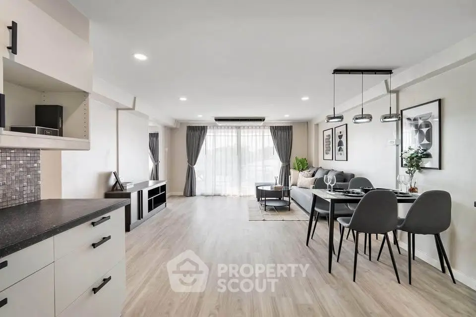 Spacious modern living room with open kitchen and elegant dining area, featuring stylish decor and ample natural light.