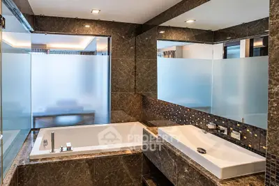 Luxurious modern bathroom with marble finishes and frosted glass accents.