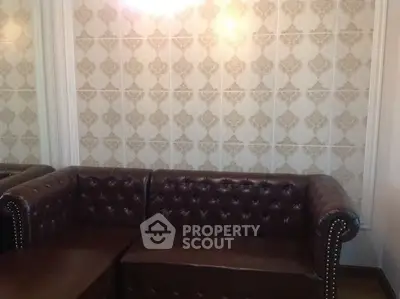 Elegant leather sofa in a stylish living room with patterned wallpaper.