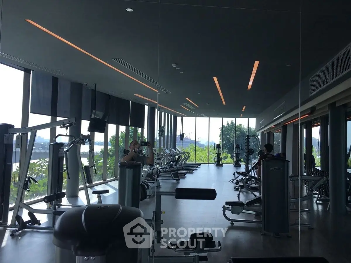 Spacious gym with modern equipment and large windows offering a scenic view.
