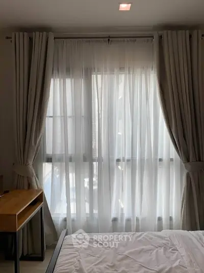 Cozy bedroom with elegant curtains and natural light, perfect for relaxation.