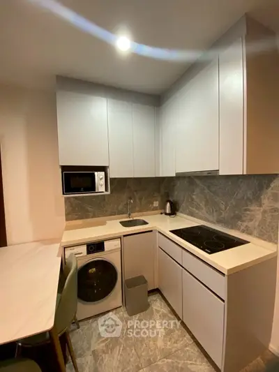 Modern kitchen with sleek cabinetry, built-in appliances, and stylish marble backsplash.