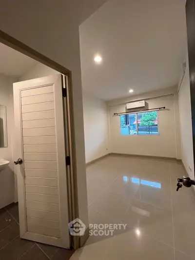 Spacious unfurnished room with large window and air conditioning, perfect for customization.