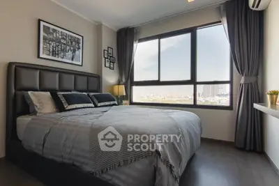 Modern bedroom with large window offering city view, stylish decor, and cozy ambiance.