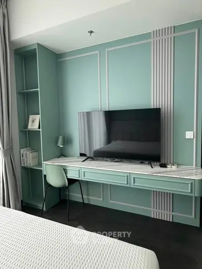 Modern bedroom with stylish built-in desk and large TV, featuring elegant teal accents and sleek design.