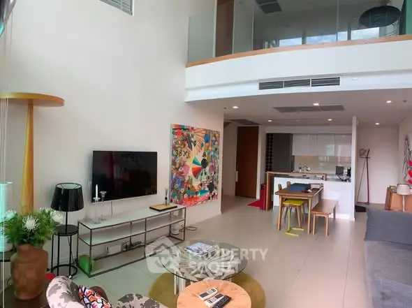 Spacious modern living room with high ceiling and open kitchen layout in a stylish apartment.