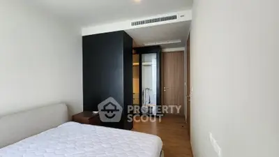 Modern bedroom with minimalist design and wooden flooring in a stylish apartment.