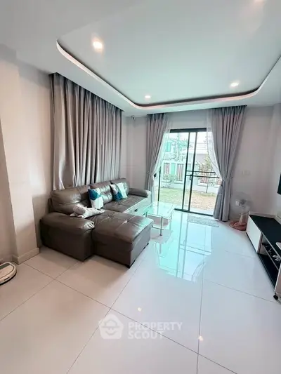 Modern living room with sleek design and large windows opening to a balcony, perfect for relaxation.