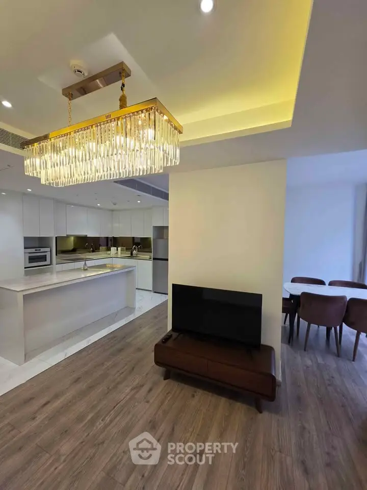 Luxurious open-plan living room with elegant chandelier and modern kitchen