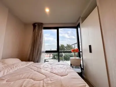 Cozy bedroom with large window offering a scenic view, modern wardrobe, and elegant decor.