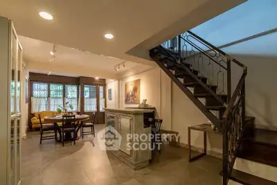 Charming open-plan living area with stylish staircase and cozy dining space.
