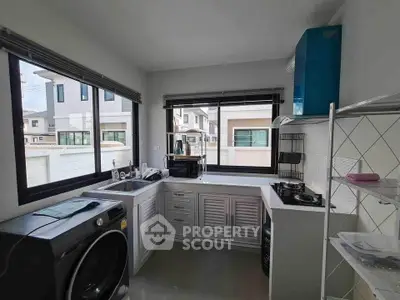 Modern kitchen with gas stove and washing machine in bright corner unit