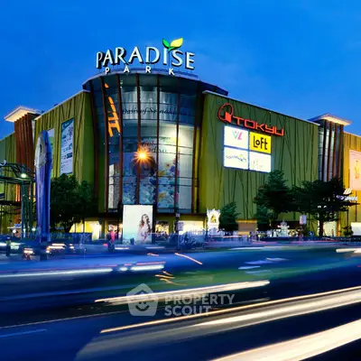 Stunning exterior view of Paradise Park shopping mall at dusk with vibrant lights and bustling street.