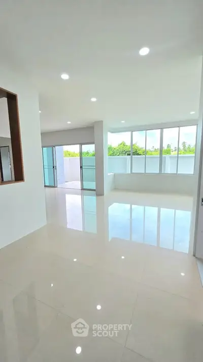 Spacious modern living room with large windows and glossy tiled floors