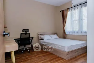 Cozy bedroom with wooden flooring and study desk, perfect for comfort and productivity.