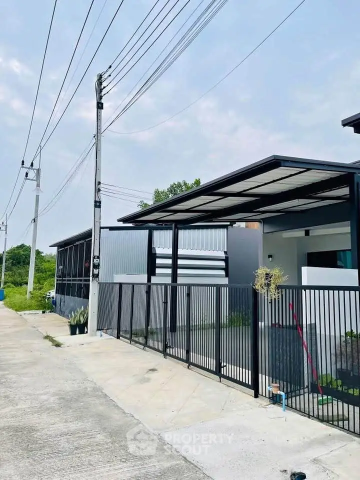 Modern minimalist house exterior with sleek metal fencing and covered carport.