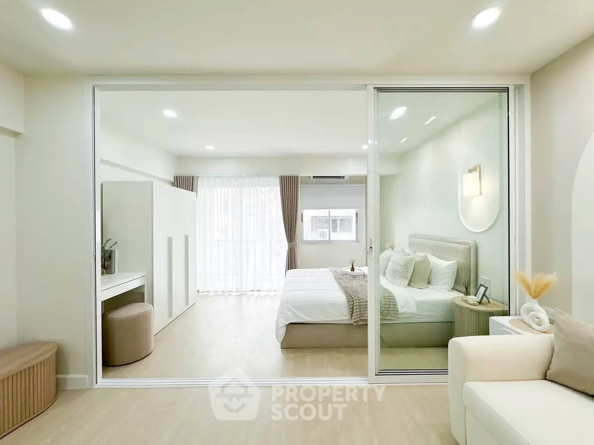 Modern bedroom with glass partition, cozy bed, and elegant decor in a bright, spacious apartment.