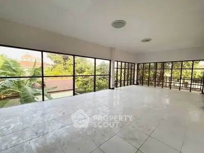 Spacious room with large windows offering lush garden views, perfect for a serene living space.