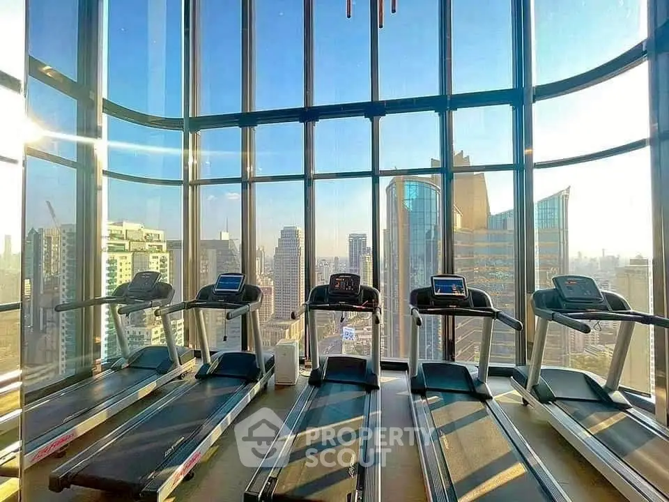 Luxurious gym with panoramic city views and modern treadmills in a high-rise building.