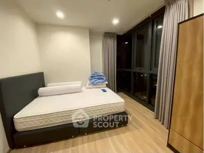 Spacious bedroom with large windows and modern decor, perfect for urban living.