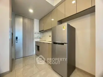 Modern kitchen with sleek cabinets and stainless steel fridge in a compact layout.