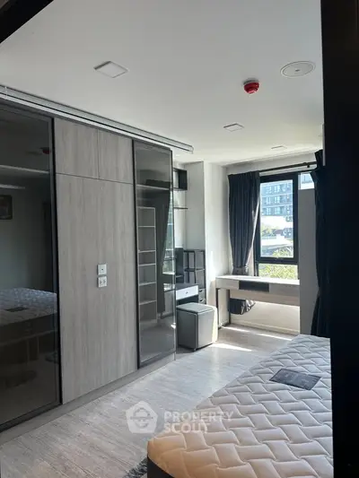Modern bedroom with large window and built-in wardrobe in a stylish apartment.