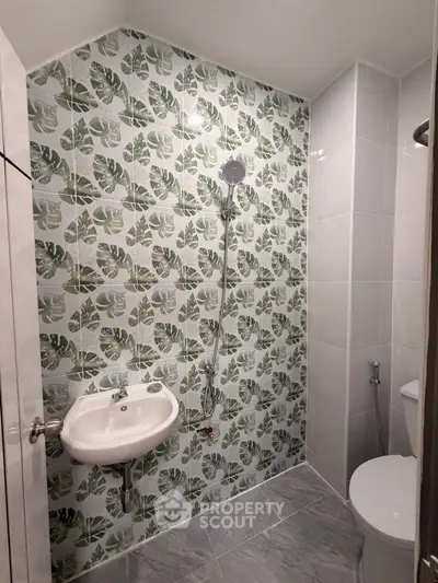 Modern bathroom with stylish leaf-patterned tiles and sleek fixtures.