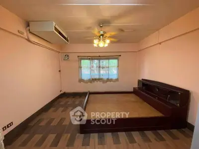 Spacious bedroom with wooden flooring and built-in bed frame, featuring a ceiling fan and air conditioning.
