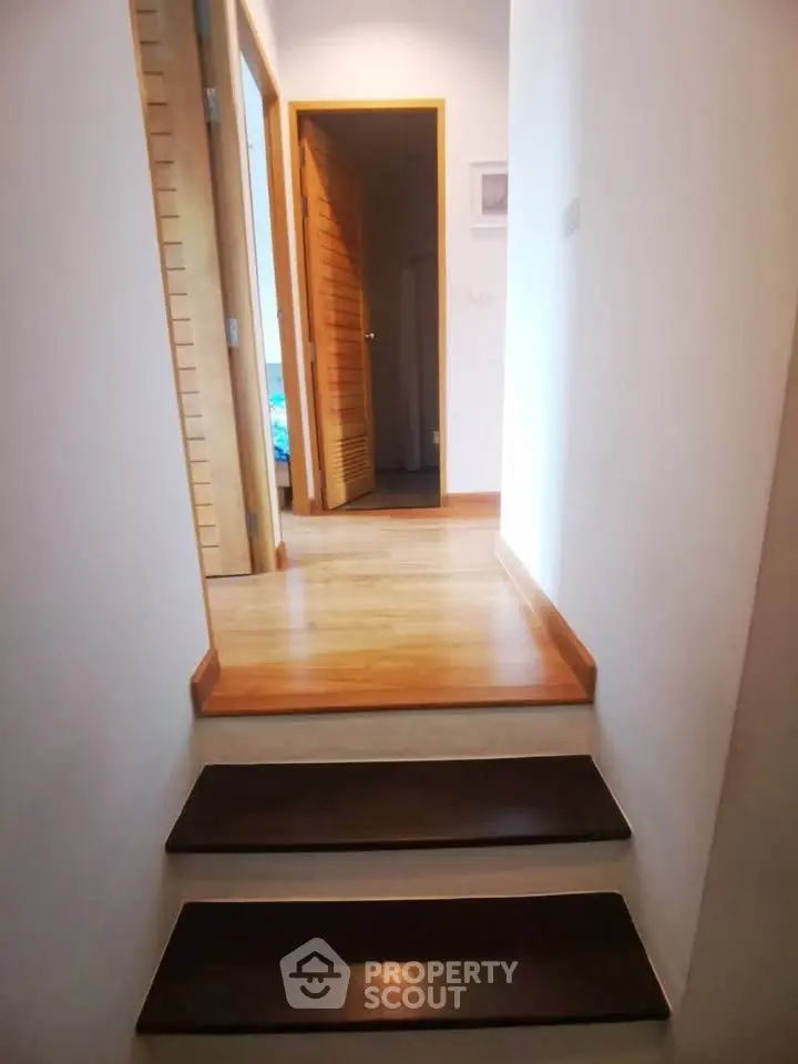 Charming hallway with wooden steps leading to cozy rooms, perfect for a modern home.