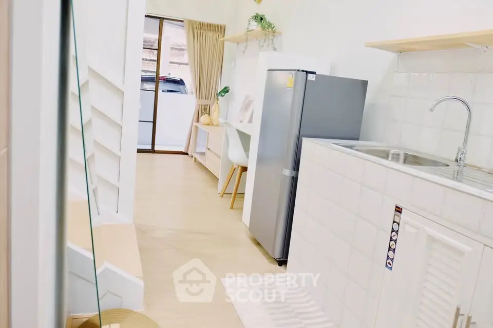 Modern kitchen with sleek design, featuring a compact fridge and stylish dining area, perfect for urban living.