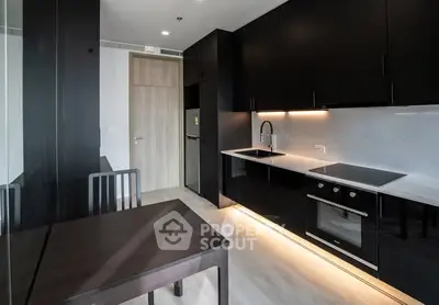 Modern kitchen with sleek black cabinets and built-in appliances in a stylish apartment.
