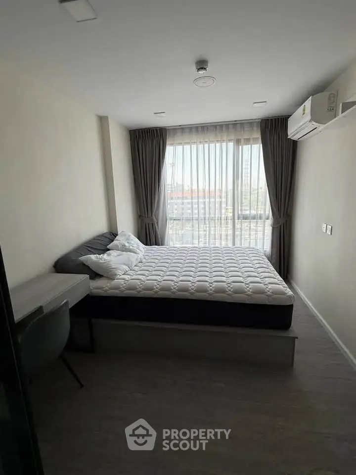 Modern bedroom with large window and natural light in a stylish apartment.