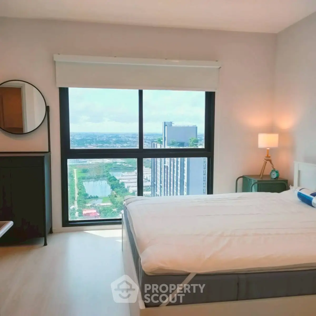 Modern bedroom with large window offering stunning city view and stylish decor.