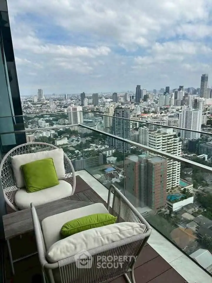 Stunning cityscape view from a high-rise balcony with cozy seating area.