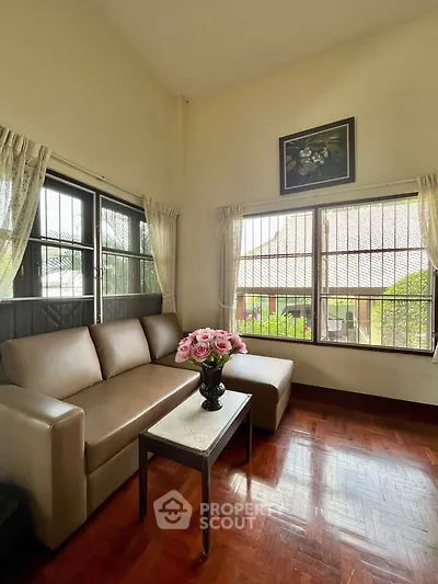 Charming living room with cozy sofa and large windows offering natural light and garden view.