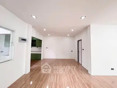 Spacious open-plan living area with modern kitchen and sleek wooden flooring