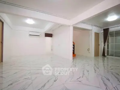 Spacious open-plan living area with elegant marble flooring and modern lighting.