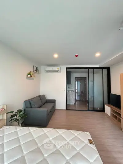 Modern living room with sleek design, featuring a cozy sofa, wall-mounted air conditioner, and sliding glass doors.