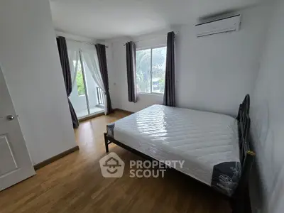 Spacious bedroom with large windows and balcony access, featuring a comfortable bed and modern air conditioning.