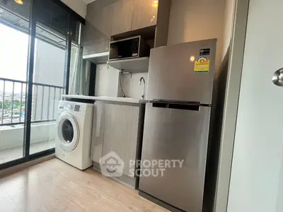 Modern compact kitchen with appliances and balcony view in urban apartment