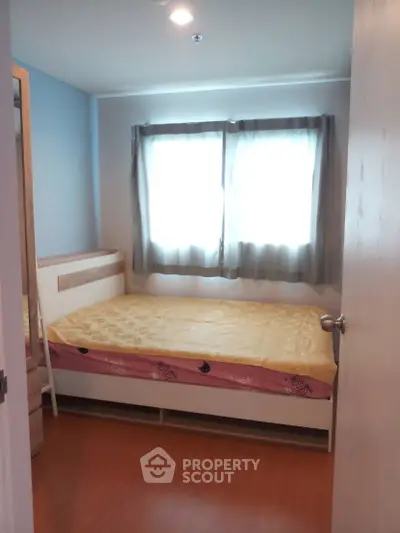 Cozy bedroom with natural light and simple furnishings, perfect for relaxation.