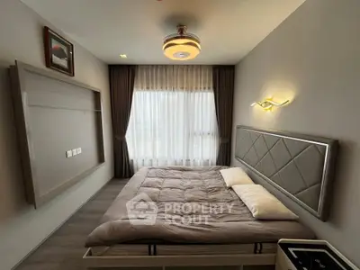 Modern bedroom with stylish decor and large window, featuring elegant lighting and cozy bedding.