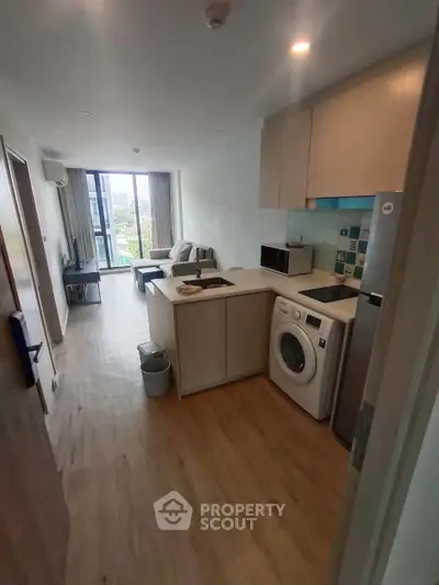 Modern apartment with open kitchen and living area, featuring a washing machine and balcony view.