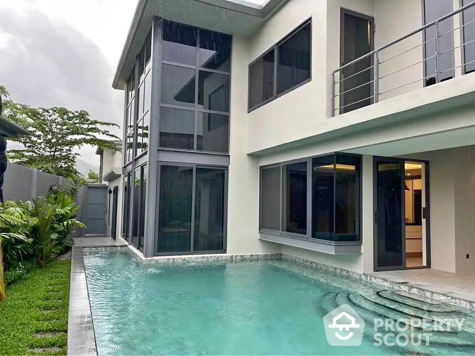 Luxurious modern home with private pool and large windows in serene setting.